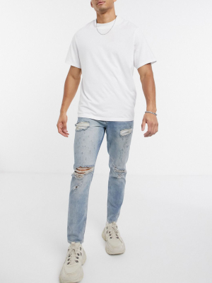 Asos Design Tapered Jeans In Vintage Light Wash Blue With Heavy Rips