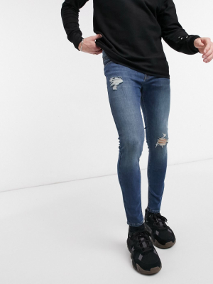 Asos Design Spray On Jeans With Power Stretch In Vintage Dark Wash Blue With Knee Rip And Abrasions