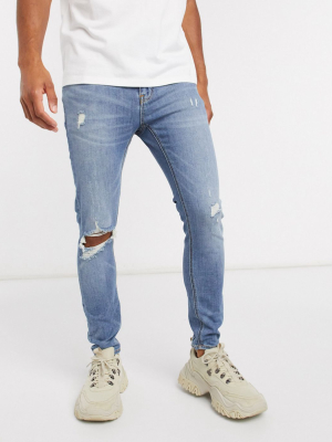 Asos Design Spray On Jeans With Power Stretch In Mid Wash Blue With Knee Rips