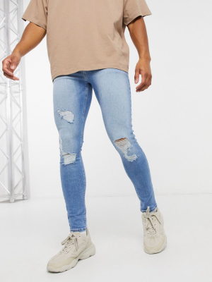 Asos Design Spray On Jeans With Power Stretch In Light Wash Blue With Heavy Rips