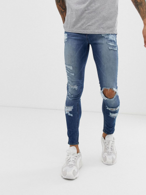 Asos Design Spray On Jeans In Power Stretch With Heavy Rips In Mid Wash Blue