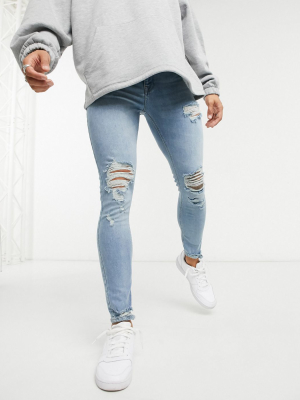 Asos Design Spray On Jeans With Power Stretch In Light Wash Blue With Heavy Rips