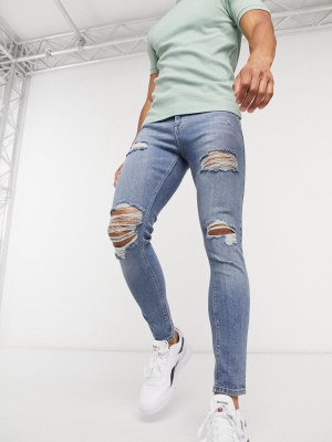 Asos Design Spray On Vintage Look Jeans With Power Stretch In Mid Blue With Heavy Rips