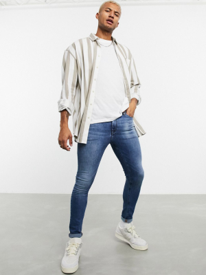 Asos Design Spray On Jeans In Power Stretch Denim In Mid Wash Blue